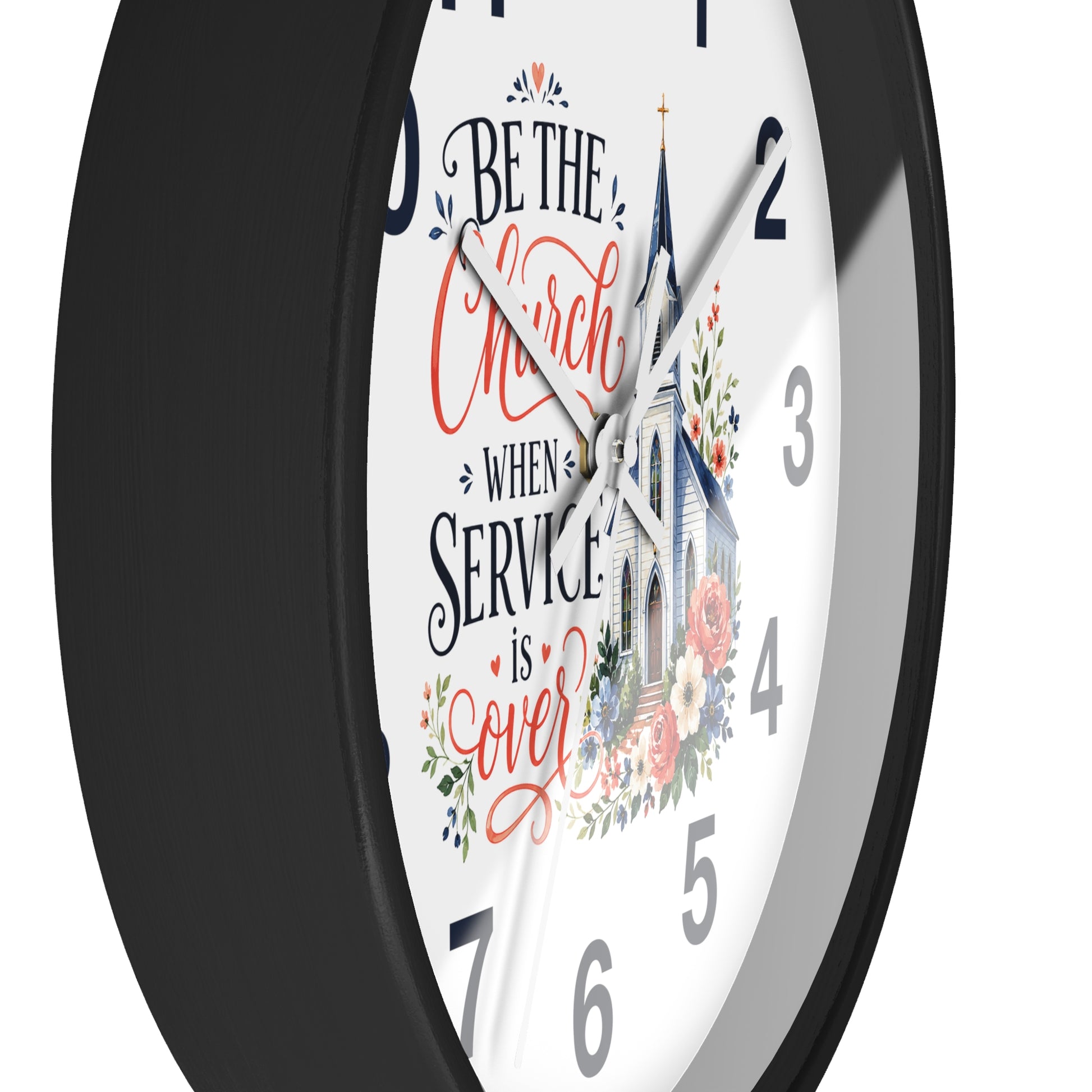 A round wall clock with a black frame and a white face featuring the phrase 'Be the Church When Service is Over' in black and coral script, alongside an illustration of a church and floral details.