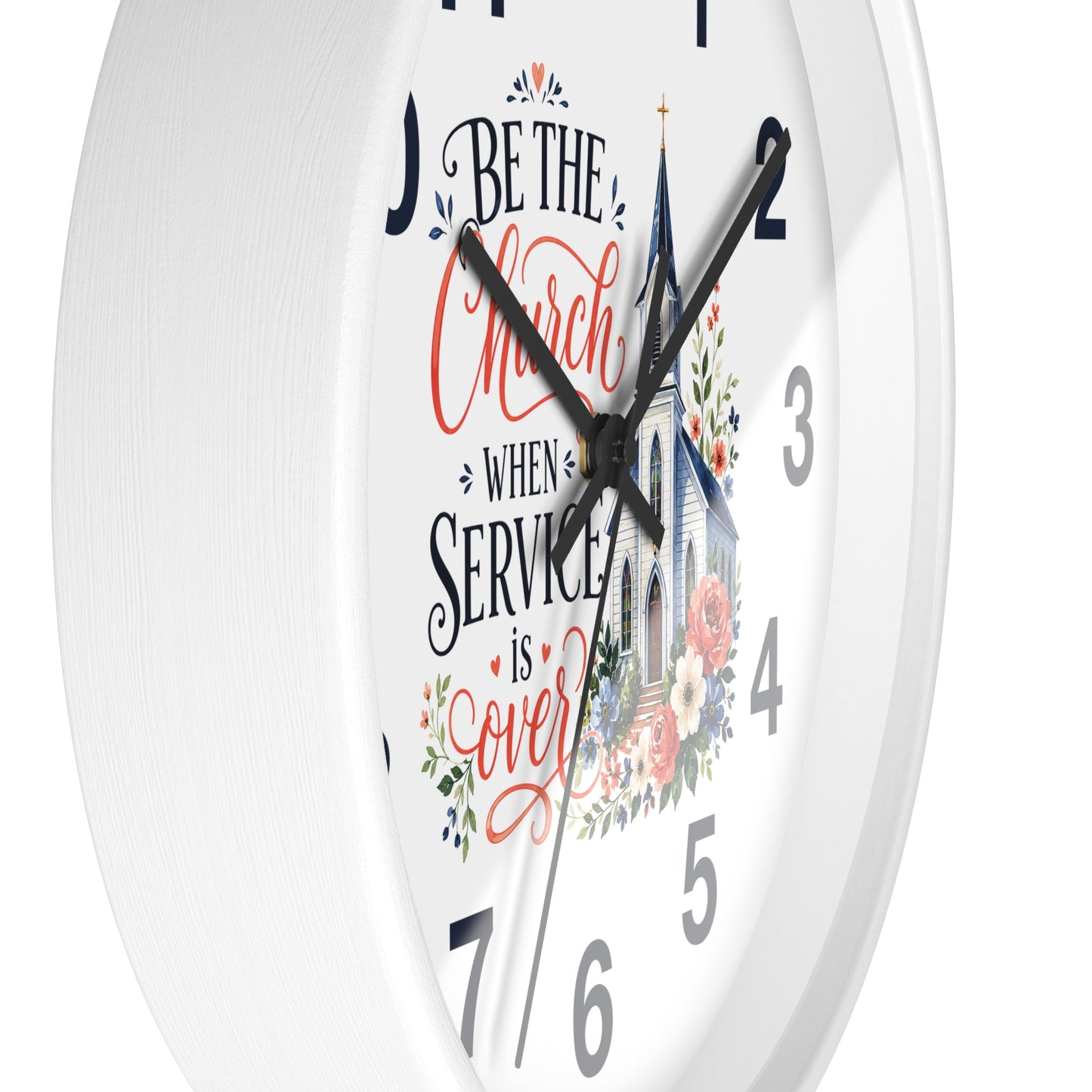 A white round wall clock with black hands and gray numerals, featuring a printed design on the face with the phrase 'Be the Church When Service is Over' in red and black script, a church illustration, and floral accents.