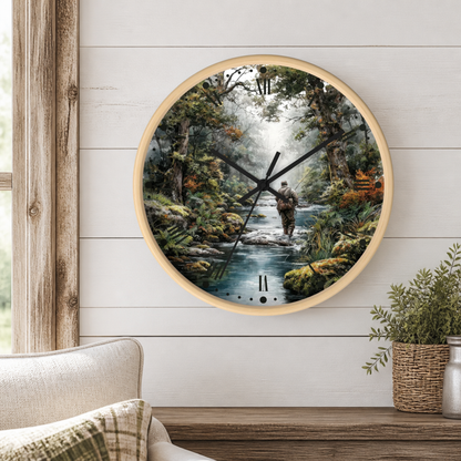 Round wall clock with a light wood frame and a printed scenic dial showing a person wading through a stream in a forest. The clock is mounted on a white shiplap wall above a wooden mantel with a plant and part of a sofa visible.