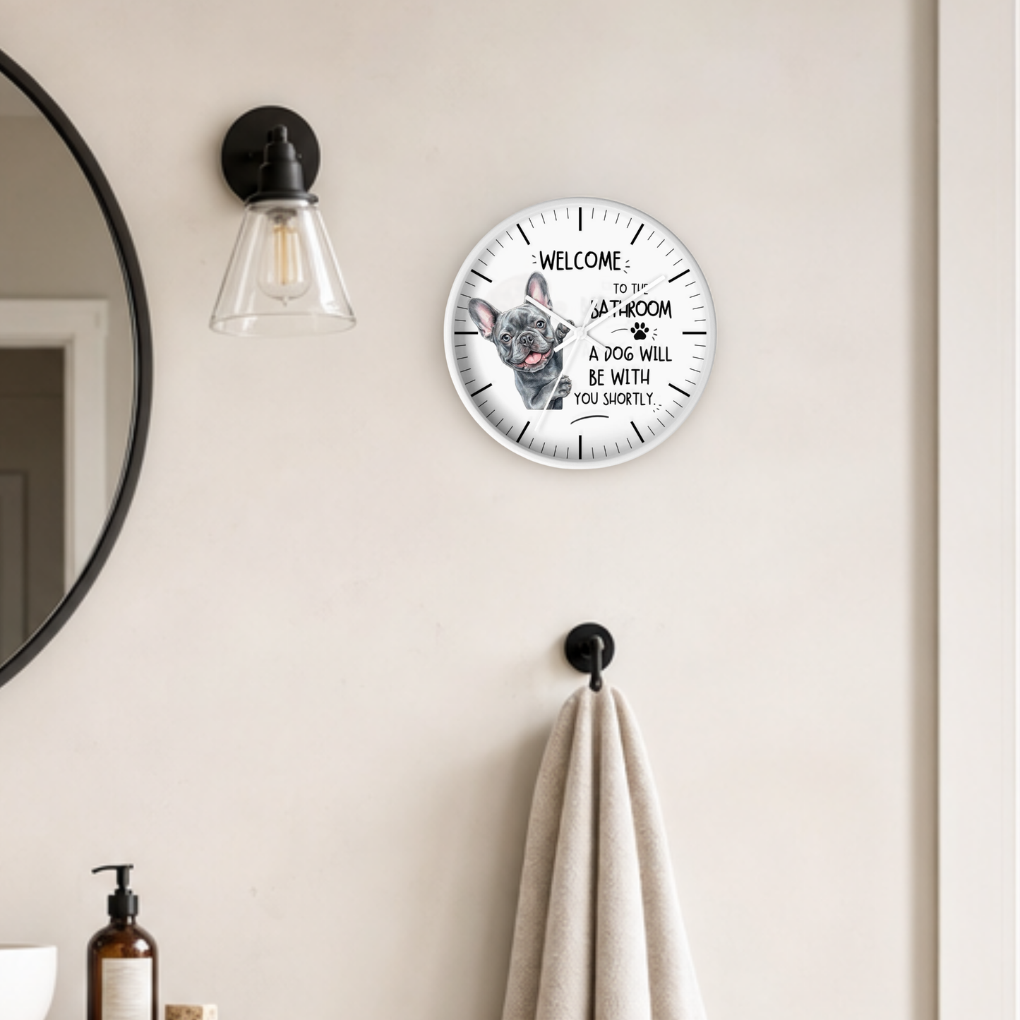 A round wall clock with a white face and black text reading 'WELCOME TO THE BATHROOM A DOG WILL BE WITH YOU SHORTLY.