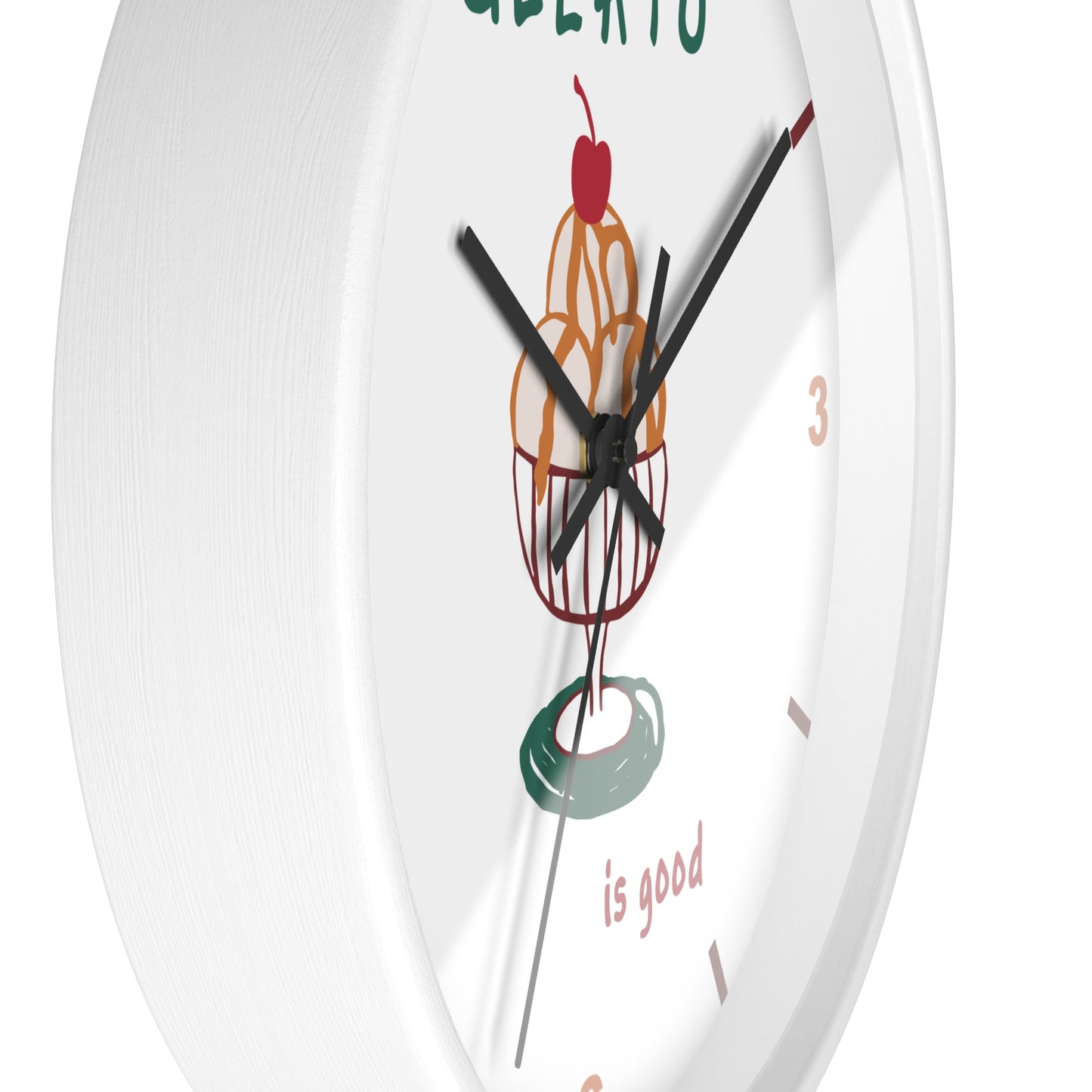A white round wall clock with black hands and a whimsical illustration of a donut with a cherry on top, plus the words 'GELATO is good' on the face.