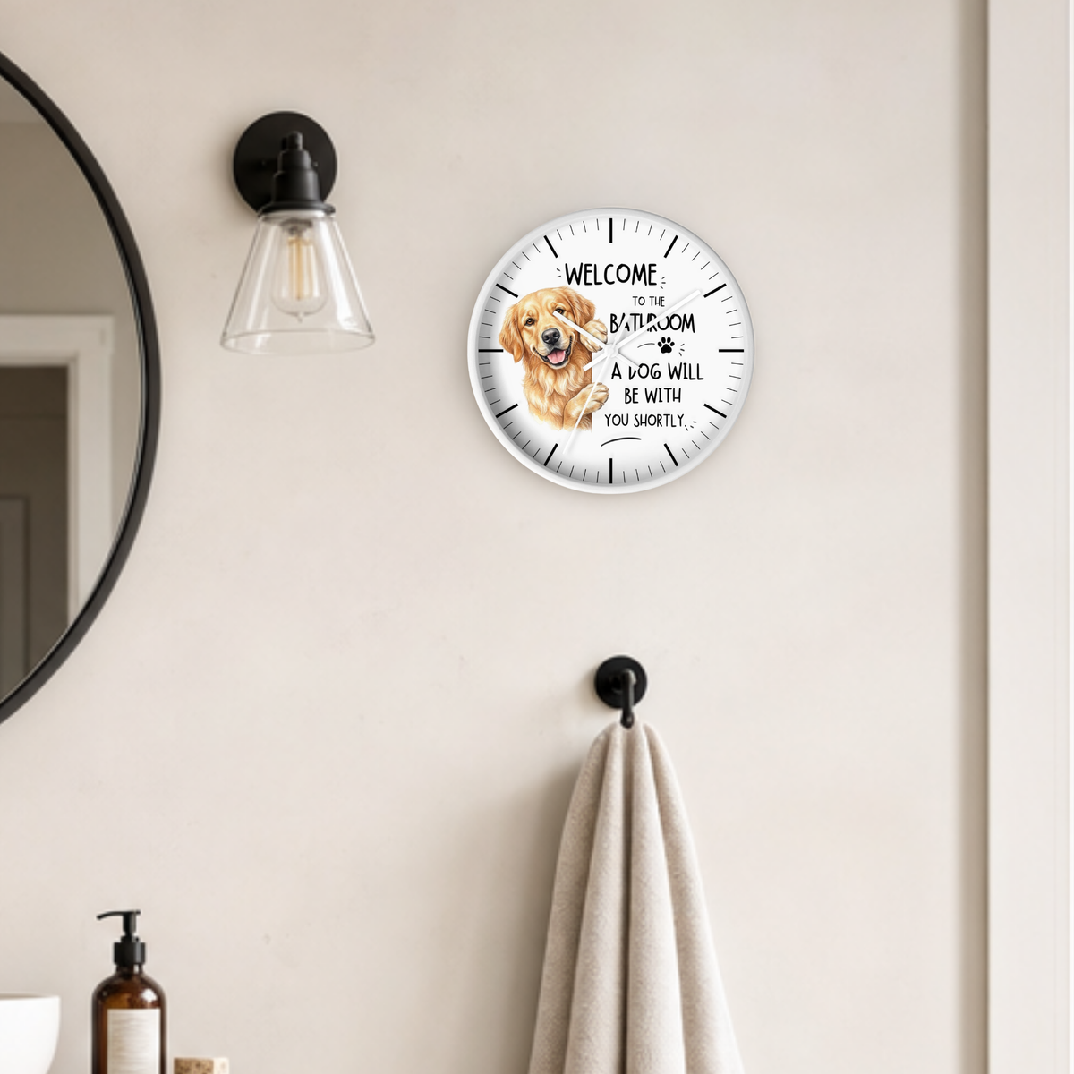 A round wall clock with a white frame, a golden retriever dog graphic and black text reading 'WELCOME TO THE BATHROOM A DOG WILL BE WITH YOU SHORTLY.