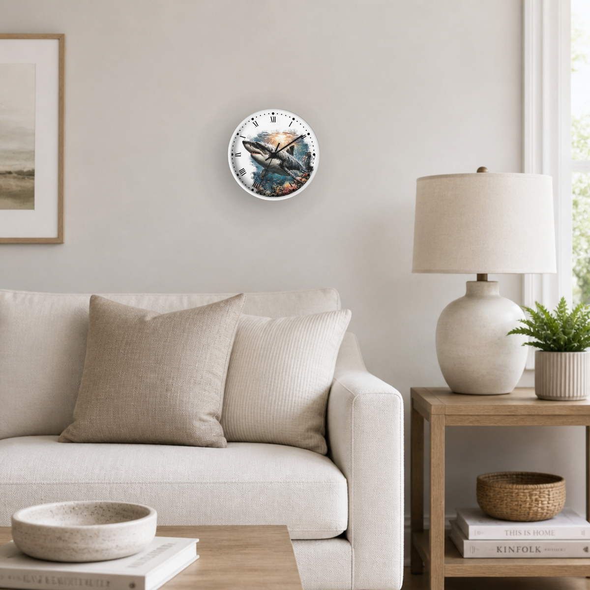 A round wall clock with a colorful ocean and shark illustration, mounted on a light beige wall in a modern living room setting with a sofa, side table, and lamp.