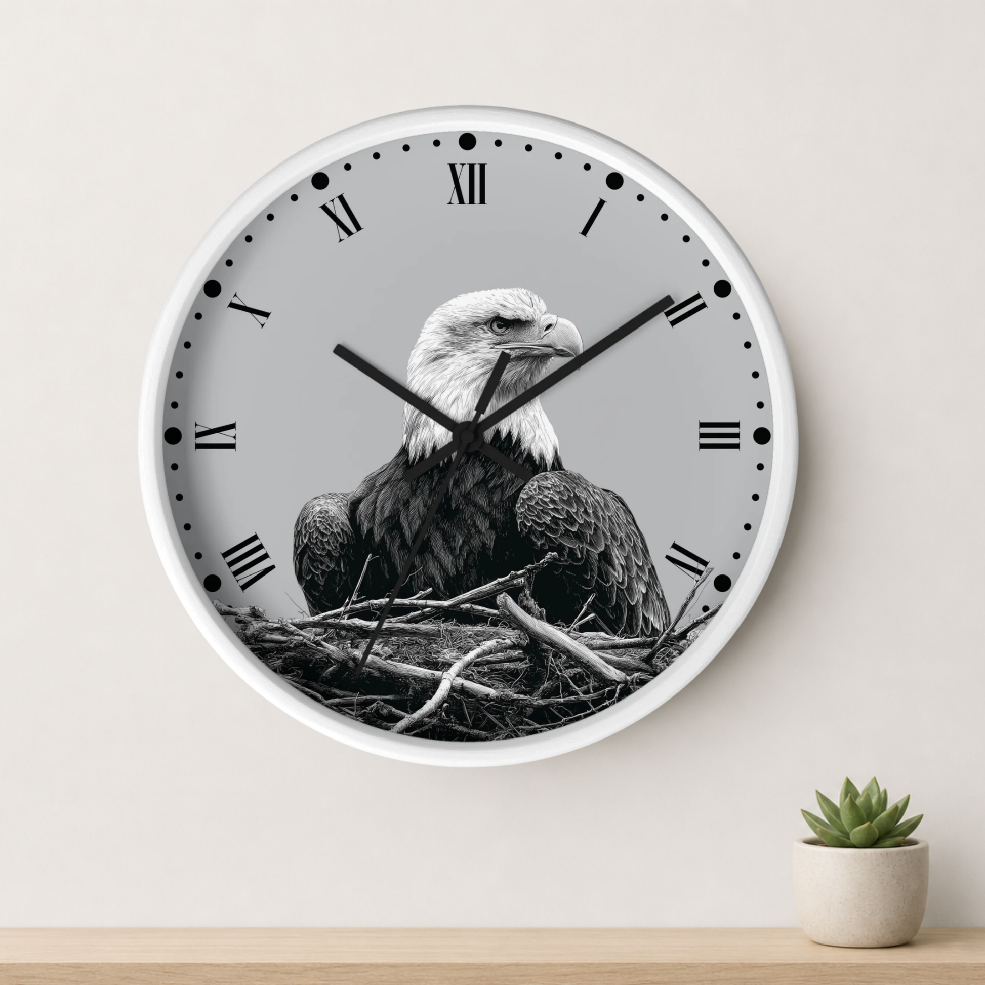 A round wall clock with a white frame and Roman numerals, featuring a black-and-white photograph of a bald eagle sitting in a nest on the clock face. The clock is mounted on a light beige wall above a wooden surface with a small potted succulent.