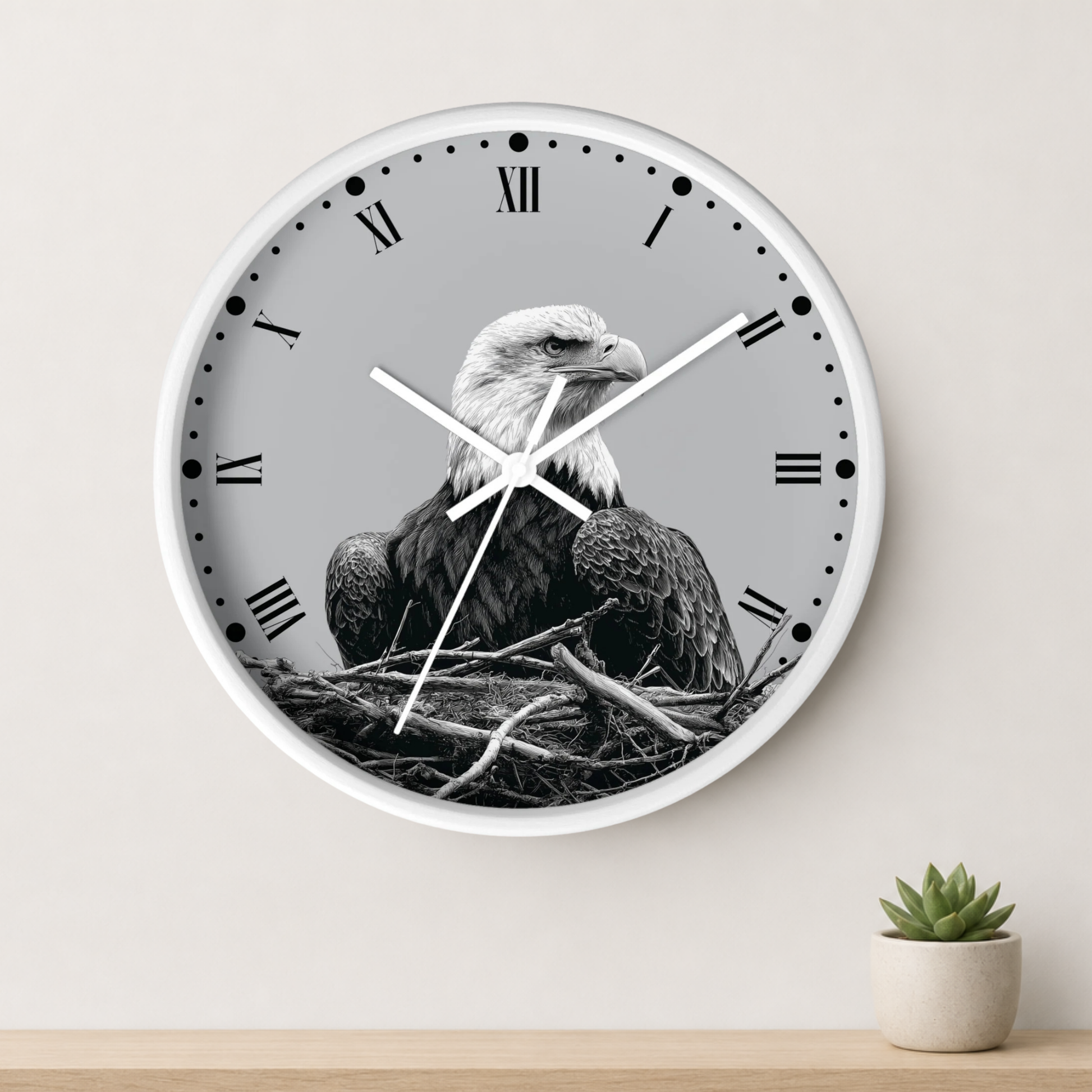 A round wall clock with a white frame and Roman numerals, featuring a black-and-white photograph of an eagle sitting in a nest. The clock is mounted on a light beige wall above a wooden shelf with a small potted succulent.
