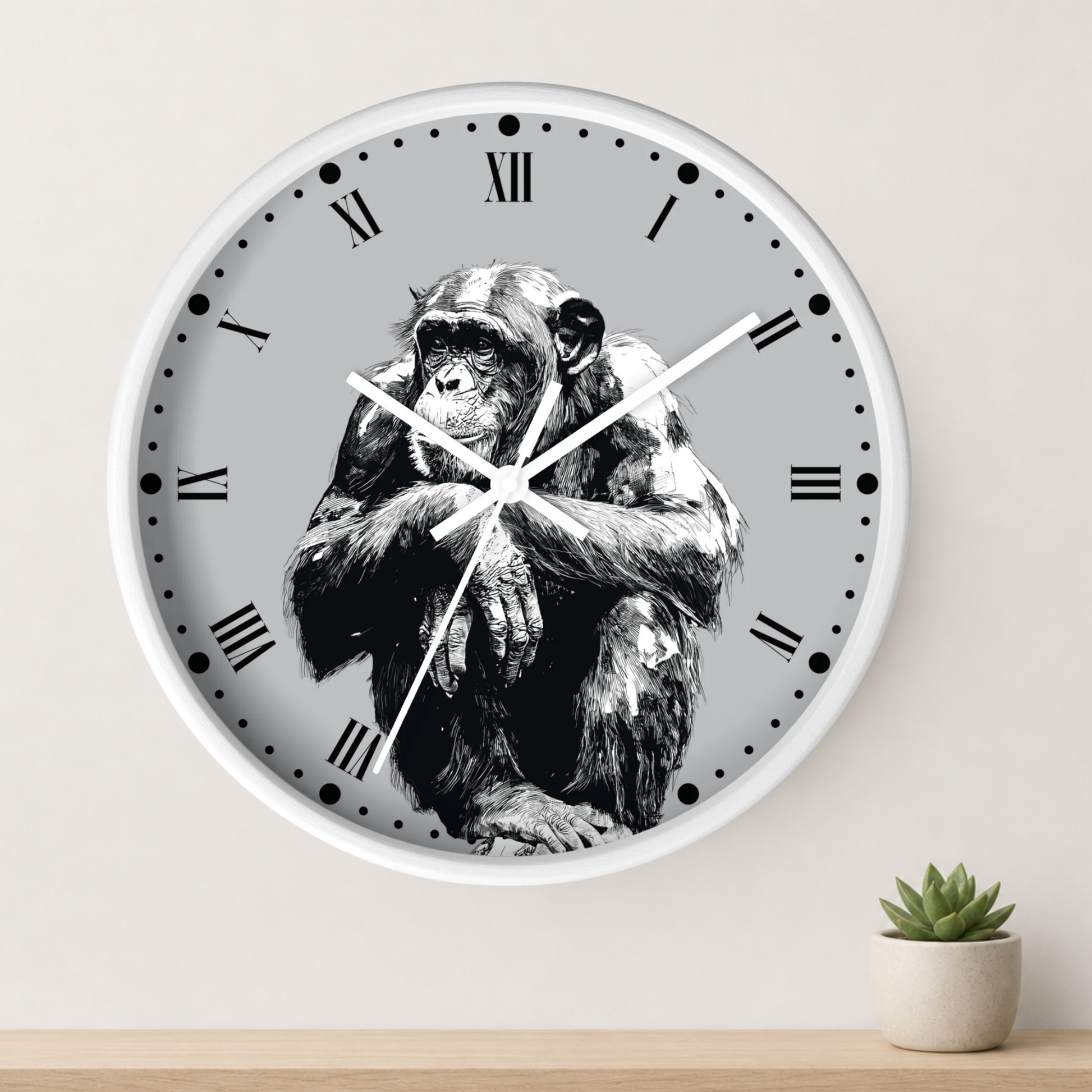 A round wall clock with a white frame and a black-and-white illustration of a chimpanzee on the face, mounted on a light wall above a small potted succulent.