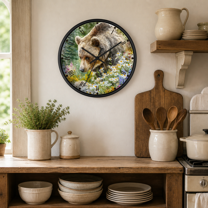 A round wall clock with a black frame hangs on a beige wall in a rustic kitchen setting. The clock face features a detailed illustration of a brown bear surrounded by colorful wildflowers.