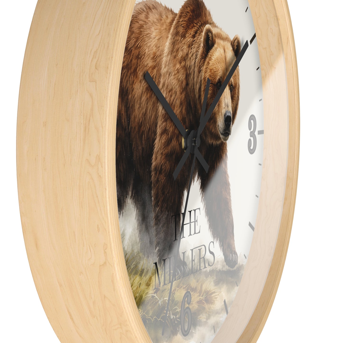 Round wall clock with a light natural wood frame and a printed face showing a large brown grizzly bear walking over rocks, with black clock hands and partial numerals visible on a white background.