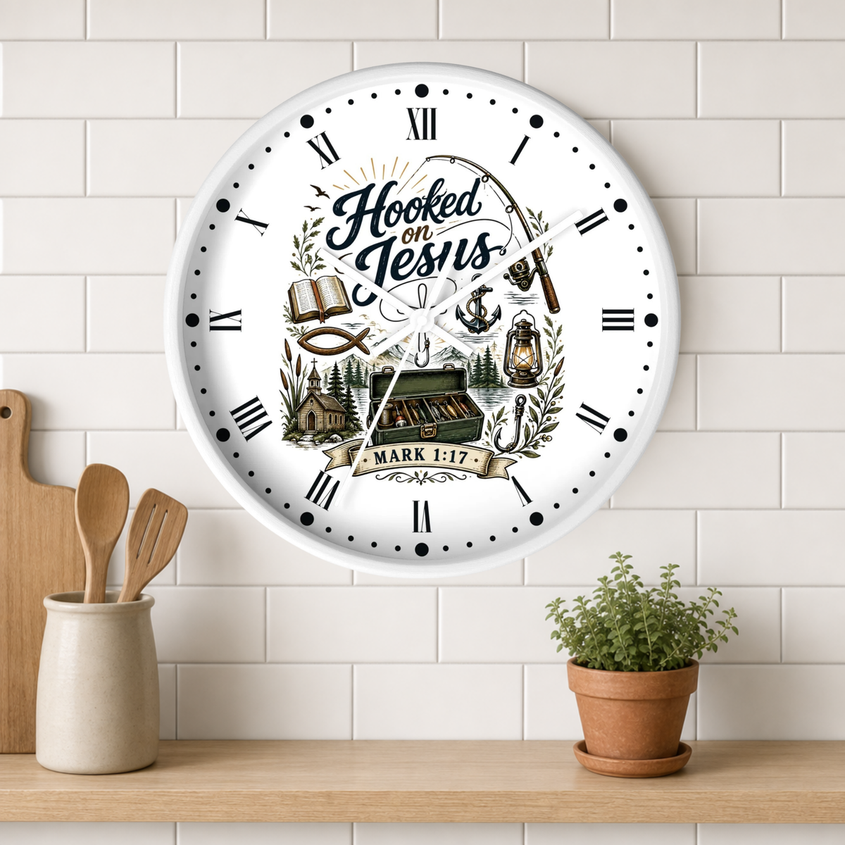 A round white wall clock with Roman numerals and a fishing-themed graphic reading 'Hooked on Jesus Mark 1:17' hangs on a white subway tile wall above a wooden shelf with kitchen utensils and a potted plant.