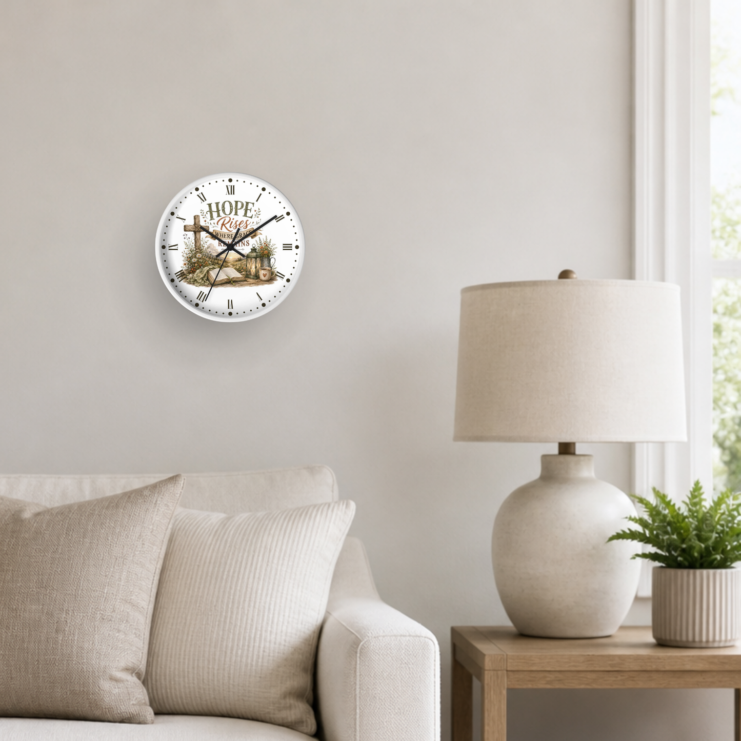 A round wall clock with a rustic cross and the word 'HOPE' hanging on a light beige wall in a styled living room setting next to a table lamp and a small potted plant.