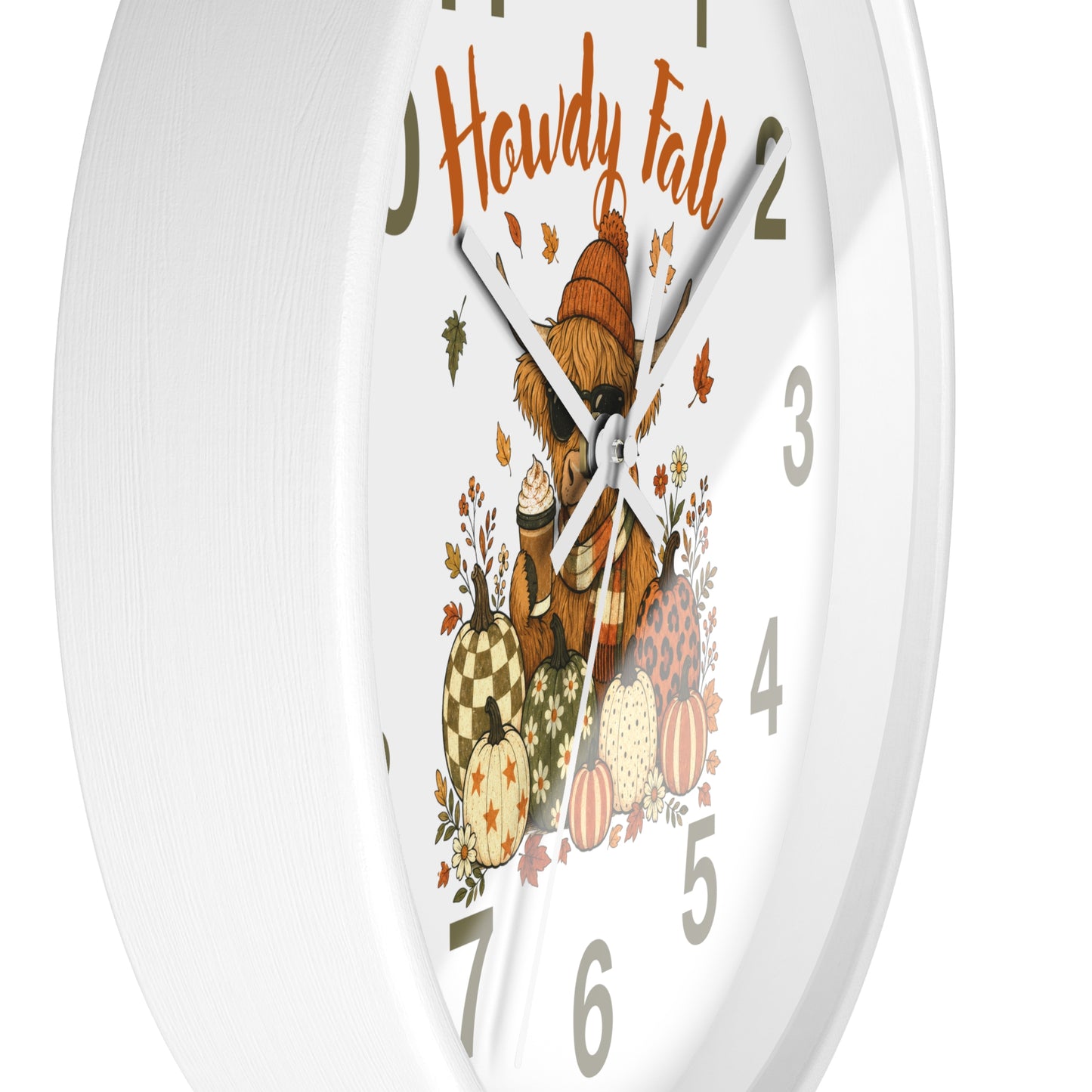 A white round wall clock with a festive autumn design. The clock face features the words 'Howdy Fall' in orange script above an illustration of a teddy bear wearing a orange hat, surrounded by pumpkins, acorns, and falling leaves.