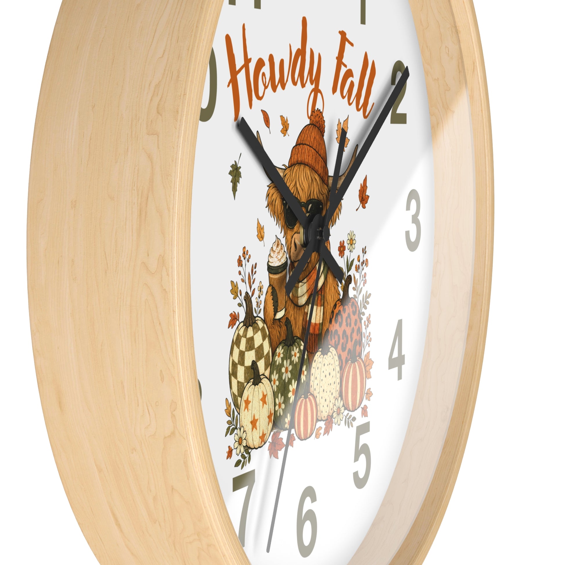 A close-up of a round wall clock with a light natural wood frame and a white face featuring an autumn illustration. The design includes the words 'Howdy Fall,' a bear in a hat, pumpkins, leaves, and gray numerals.