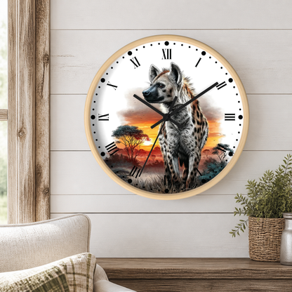 A round wall clock with a light wood frame hangs on a white paneled wall above a wooden table. The clock face features a detailed illustration of a spotted hyena standing in a savanna landscape at sunset, with black Roman numerals and black clock hands.