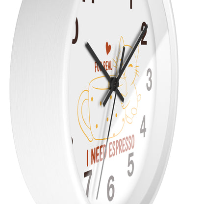A close-up of a white wall clock with black hands, gray numerals, and a coffee-themed illustration featuring a cup, cat outline, red heart, and the text 'FOR REAL I NEED ESPRESSO'.