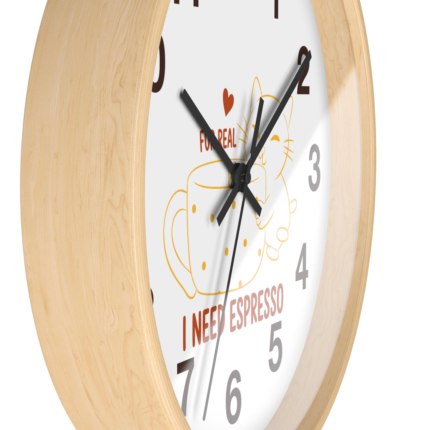 A close-up of a round wall clock with a light natural wood frame and a white face. The clock face features a minimalist illustration of a coffee cup and cat, the text 'FOR REAL' with a small red heart, and 'I NEED ESPRESSO' in red.
