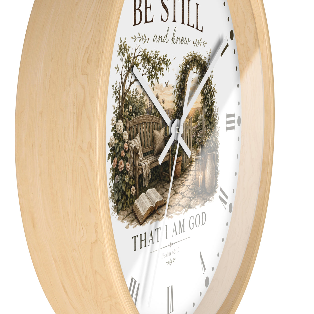A round wall clock with a light natural wood frame and a white face featuring a vintage-style illustration of a garden bench under an arched trellis, with the text 'BE STILL and know' and 'THAT I AM GOD'.