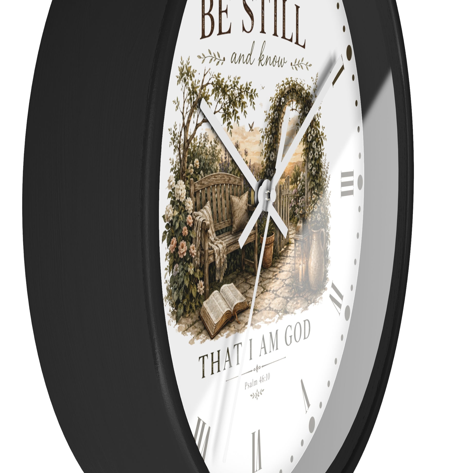 A round wall clock with a black frame and a white face featuring a vintage-style illustration of a garden bench beneath an arched floral trellis, with the text 'BE STILL and know' and 'THAT I AM GOD' on a white background.