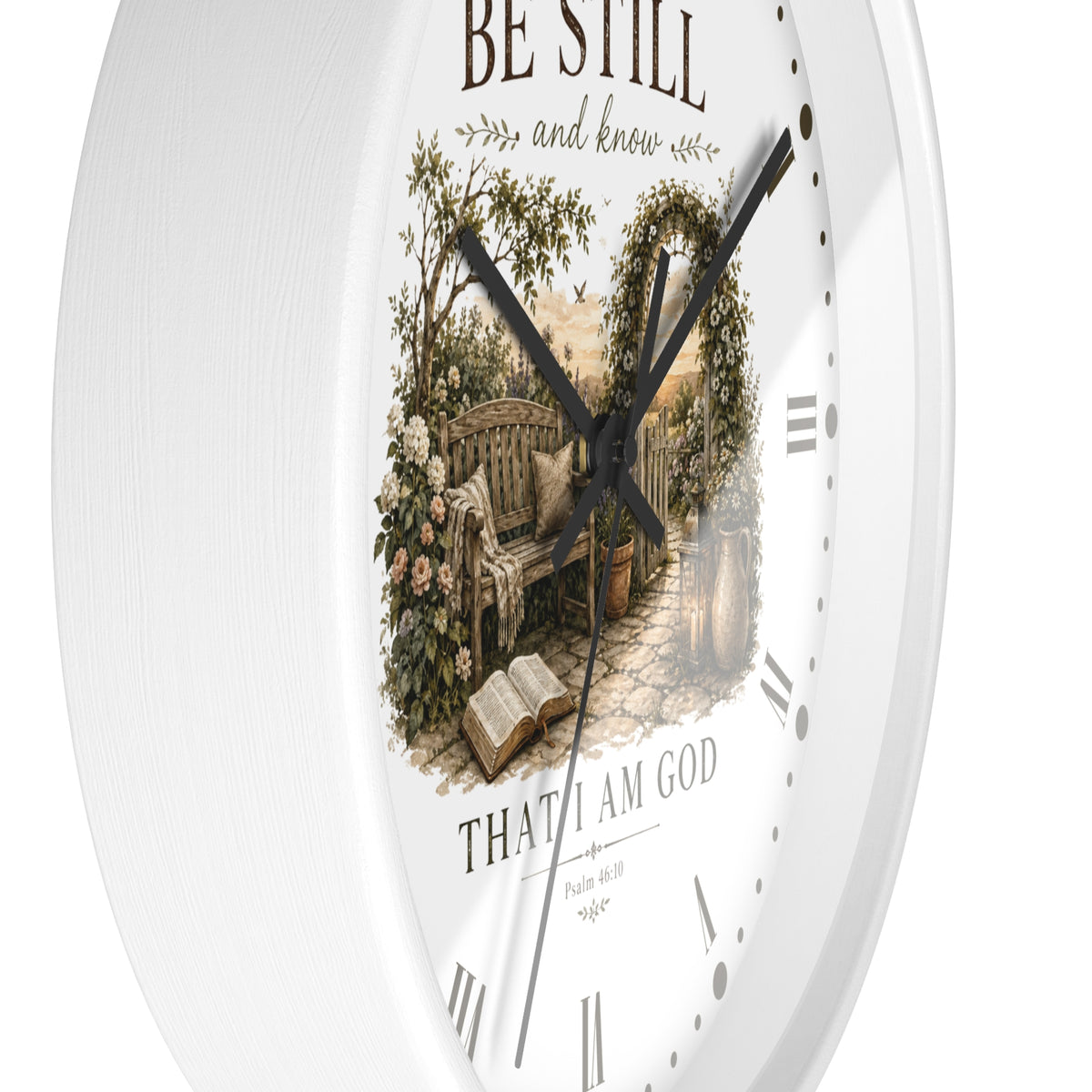 White round wall clock with a vintage-style garden bench illustration in the center and the words 'BE STILL and know' and 'THAT I AM GOD' on the dial.
