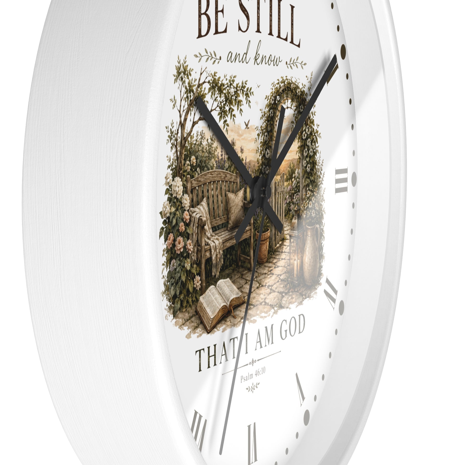 White round wall clock with a vintage-style garden bench illustration in the center and the words 'BE STILL and know' and 'THAT I AM GOD' on the dial.