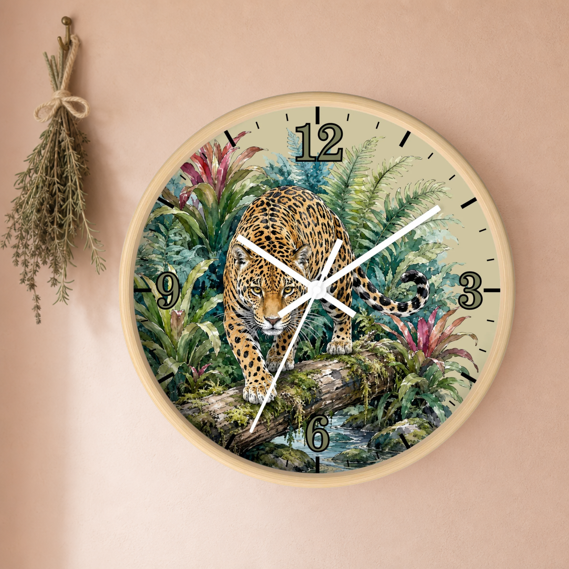 Round wall clock with a natural wood frame and a detailed illustration of a leopard in a lush jungle on the face, mounted on a beige wall with a dried herb sprig hanging to the left.