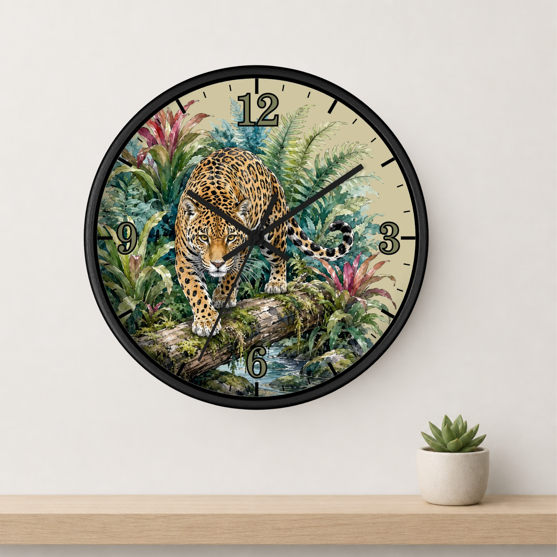 A round wall clock with a black frame and a detailed illustration of a leopard in a lush jungle scene. The clock is mounted on a white wall above a light wood shelf with a small potted succulent.