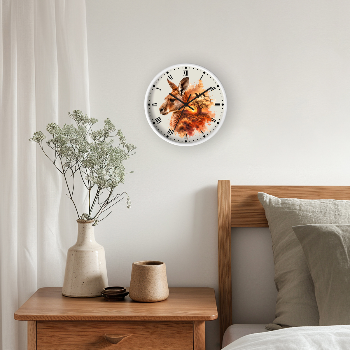A round wall clock with a white face and black Roman numerals, featuring a detailed illustration of a kangaroo in warm orange and brown tones, hanging on a light gray wall above a wooden nightstand with a vase of dried flowers.