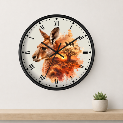 A round wall clock with a black frame and a white face featuring a kangaroo illustration over an orange autumn landscape. The clock is mounted on a light gray wall above a wooden shelf with a small potted succulent.
