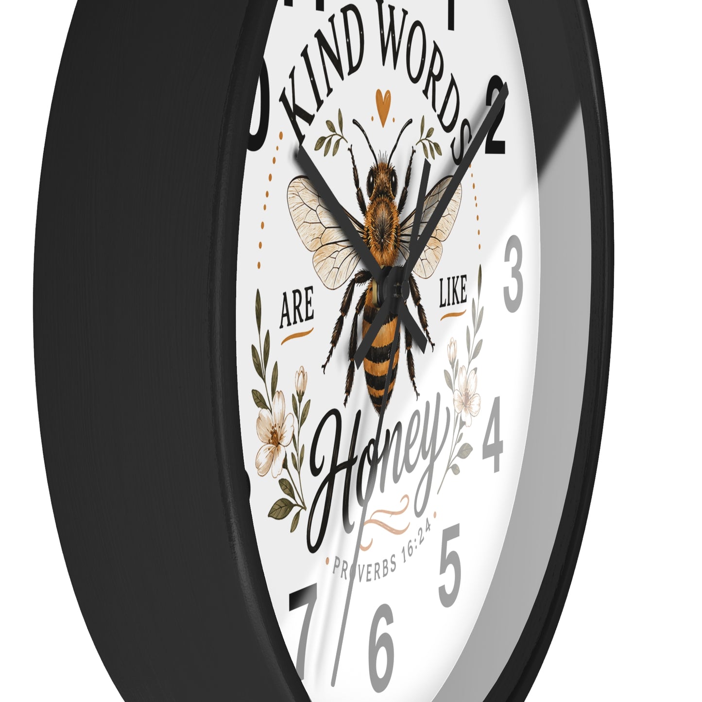 A close-up of a round wall clock with a black frame and a white face featuring a honeybee illustration, floral details, and the quote 'Kind words are like honey' with 'Honey' in script.