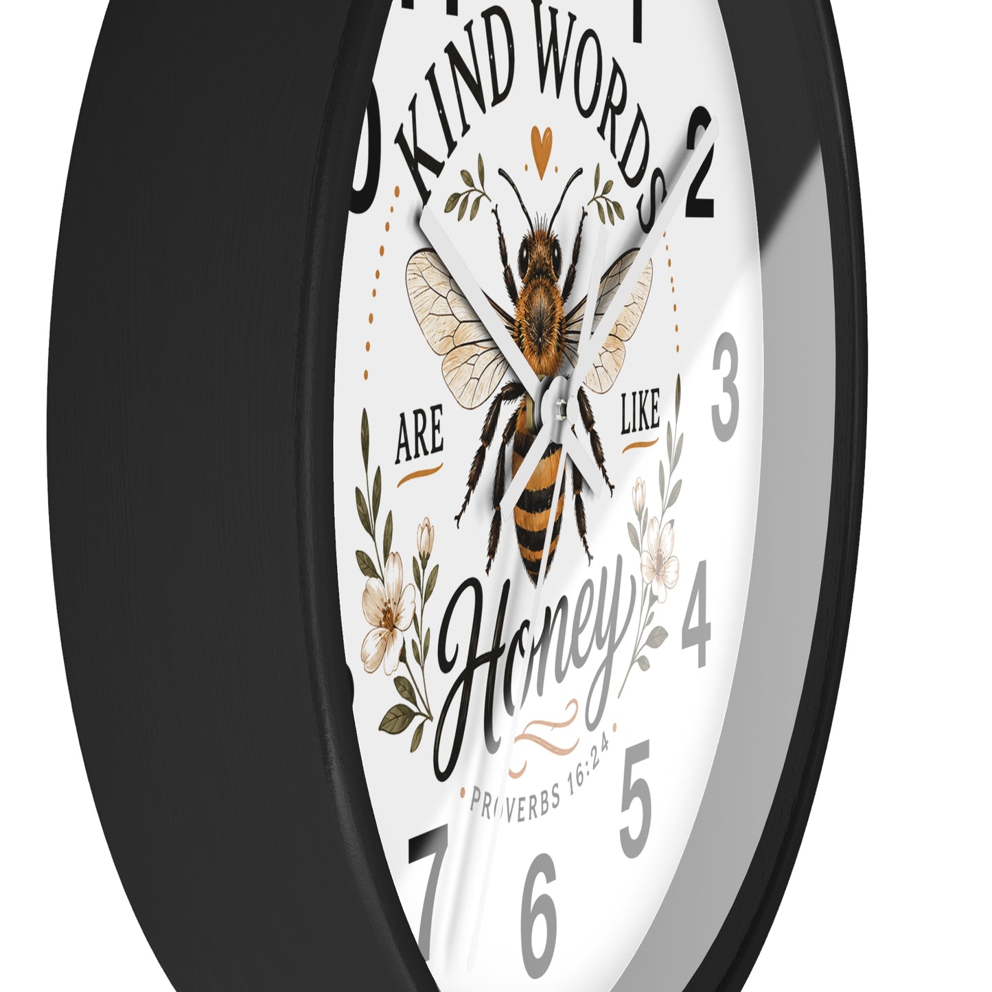 A round wall clock with a black frame and a white face featuring a bee illustration, floral details, and the quote 'Kind words are like honey' with scripture text.