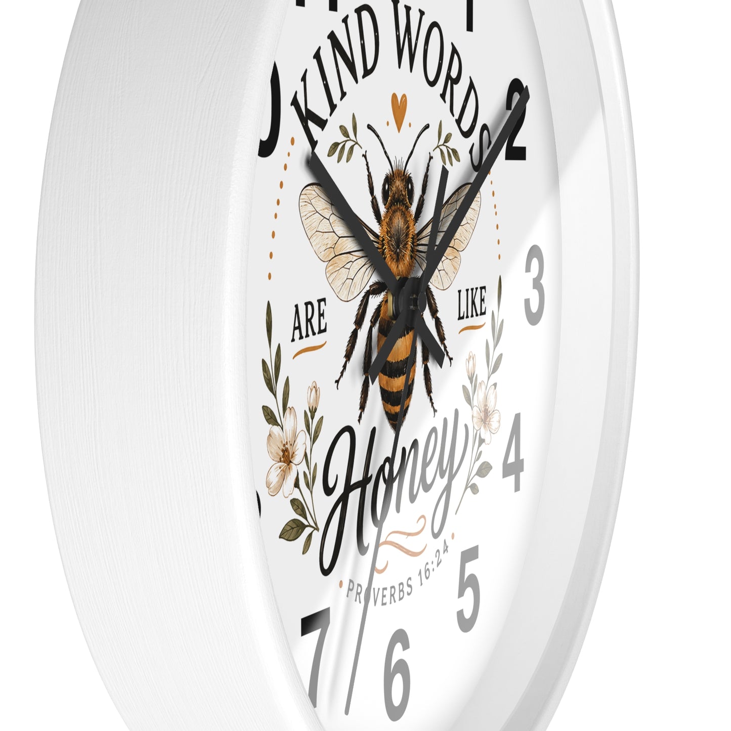 A white round wall clock with a printed bee and floral design on the face, featuring the quote 'Kind Words Are Like Honey' and black Arabic numerals.