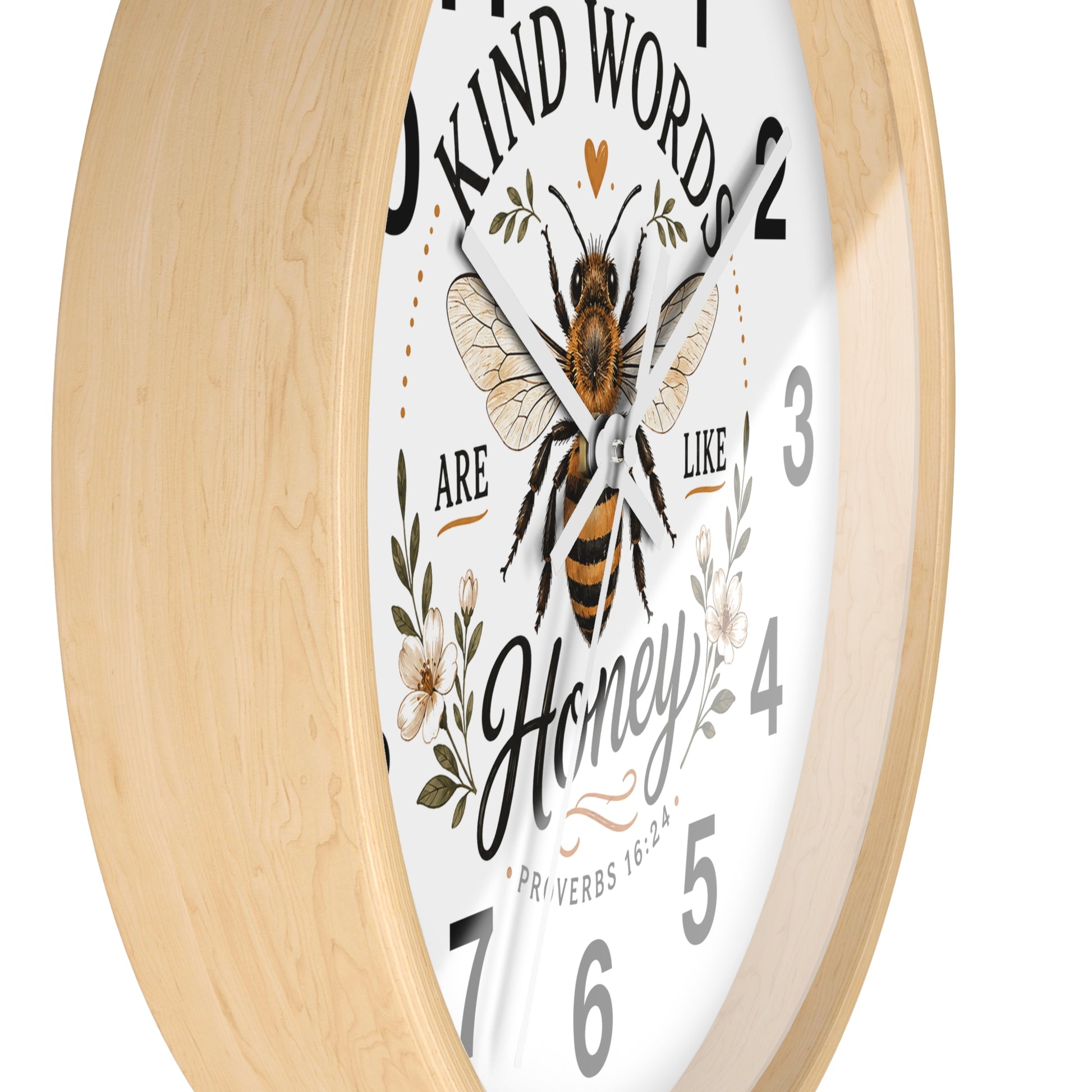 A close-up of a round wall clock with a light natural wood frame and a white face. The clock face features a detailed illustration of a honeybee, floral elements, and the text 'KIND WORDS ARE LIKE Honey' with numbers in black.