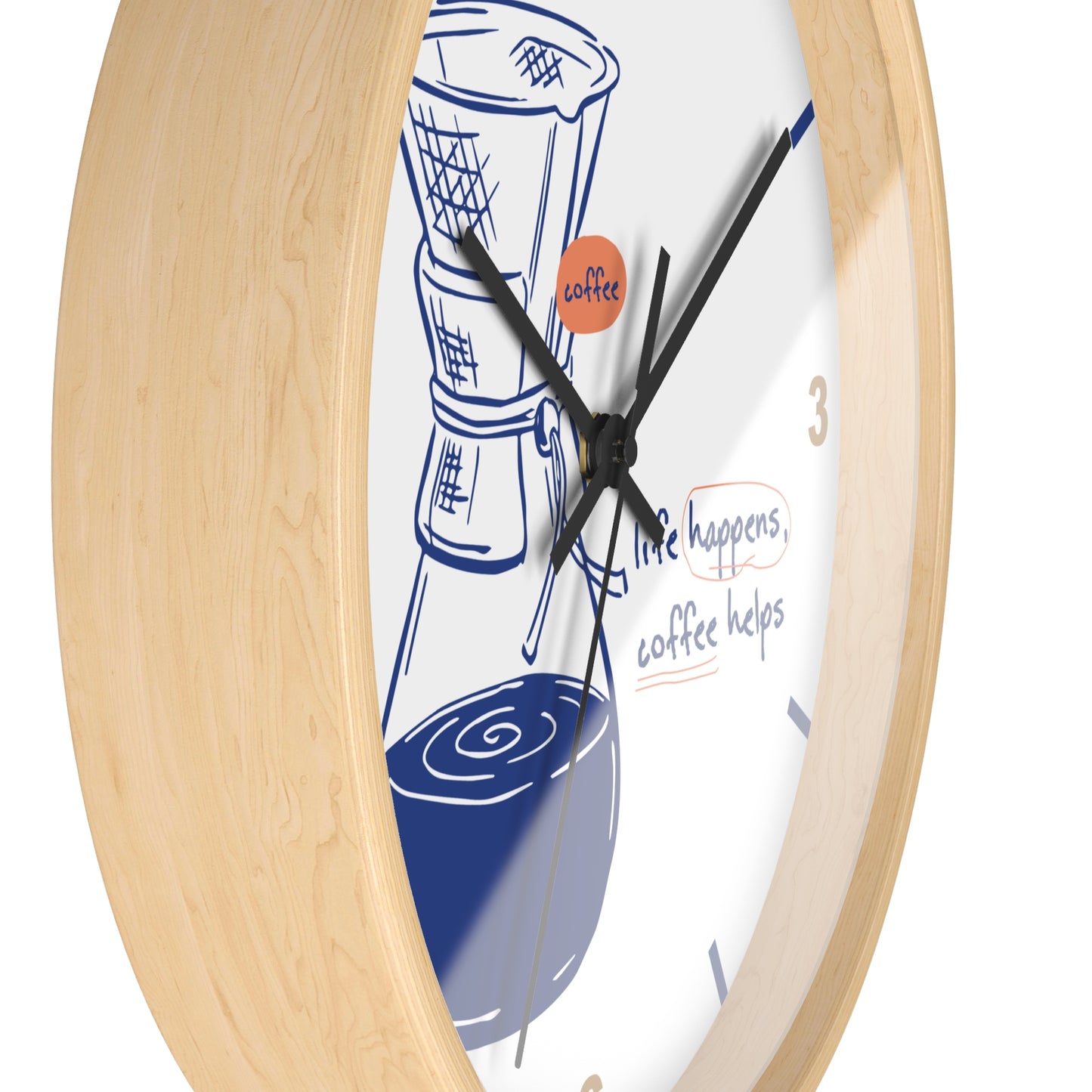 A close-up of a wall clock with a light natural wood frame and a white face featuring a blue coffee cup illustration, black hands, and the phrase 'life happens, coffee helps' on a white background.