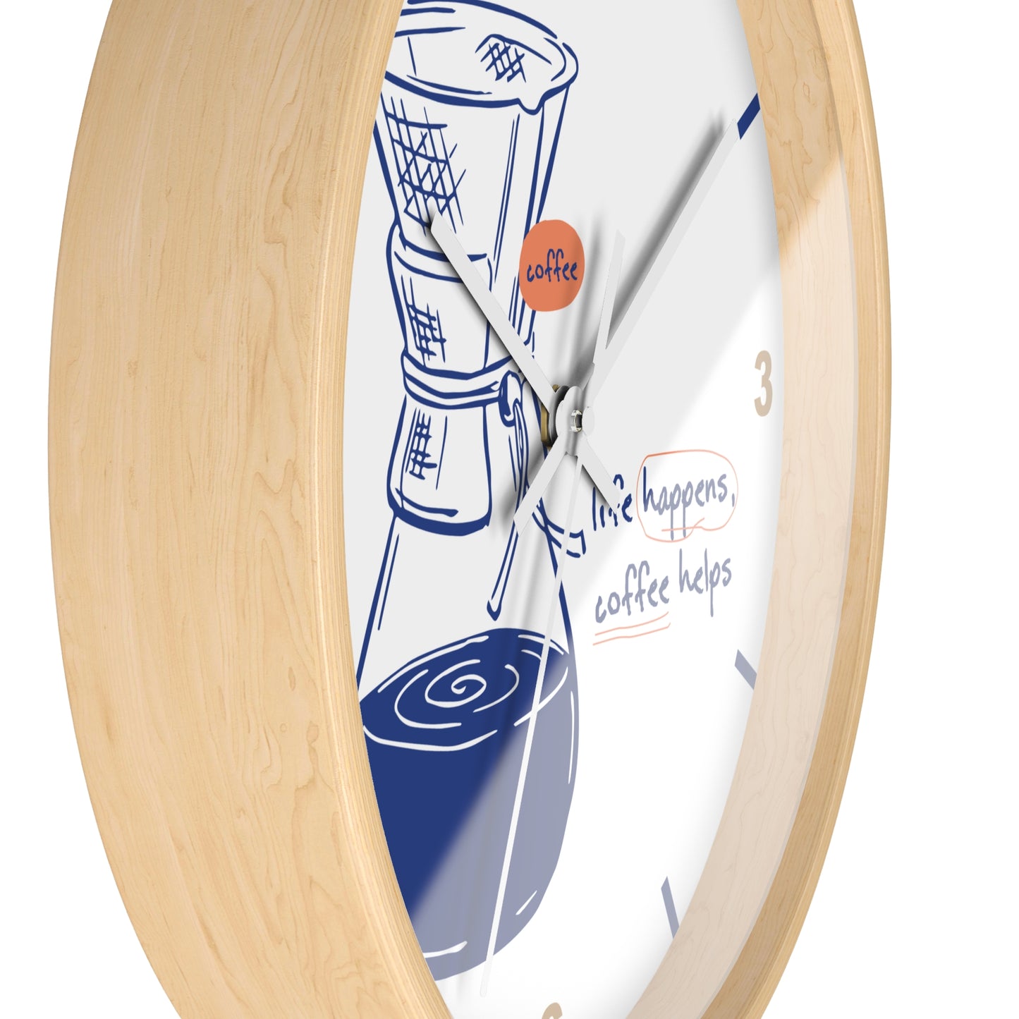A close-up of a round wall clock with a light natural wood frame and a white face. The clock face features a blue line drawing of a coffee maker and coffee cups, with the phrase 'life happens, coffee helps' and a small orange circle containing the word 'coffee'.