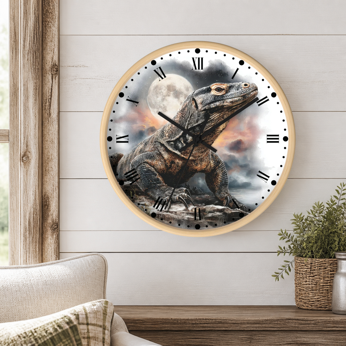Round wall clock with a light wood frame featuring a detailed illustration of a large Komodo dragon under a full moon, mounted on a white shiplap wall above a wooden console table with a plant and part of a sofa visible.