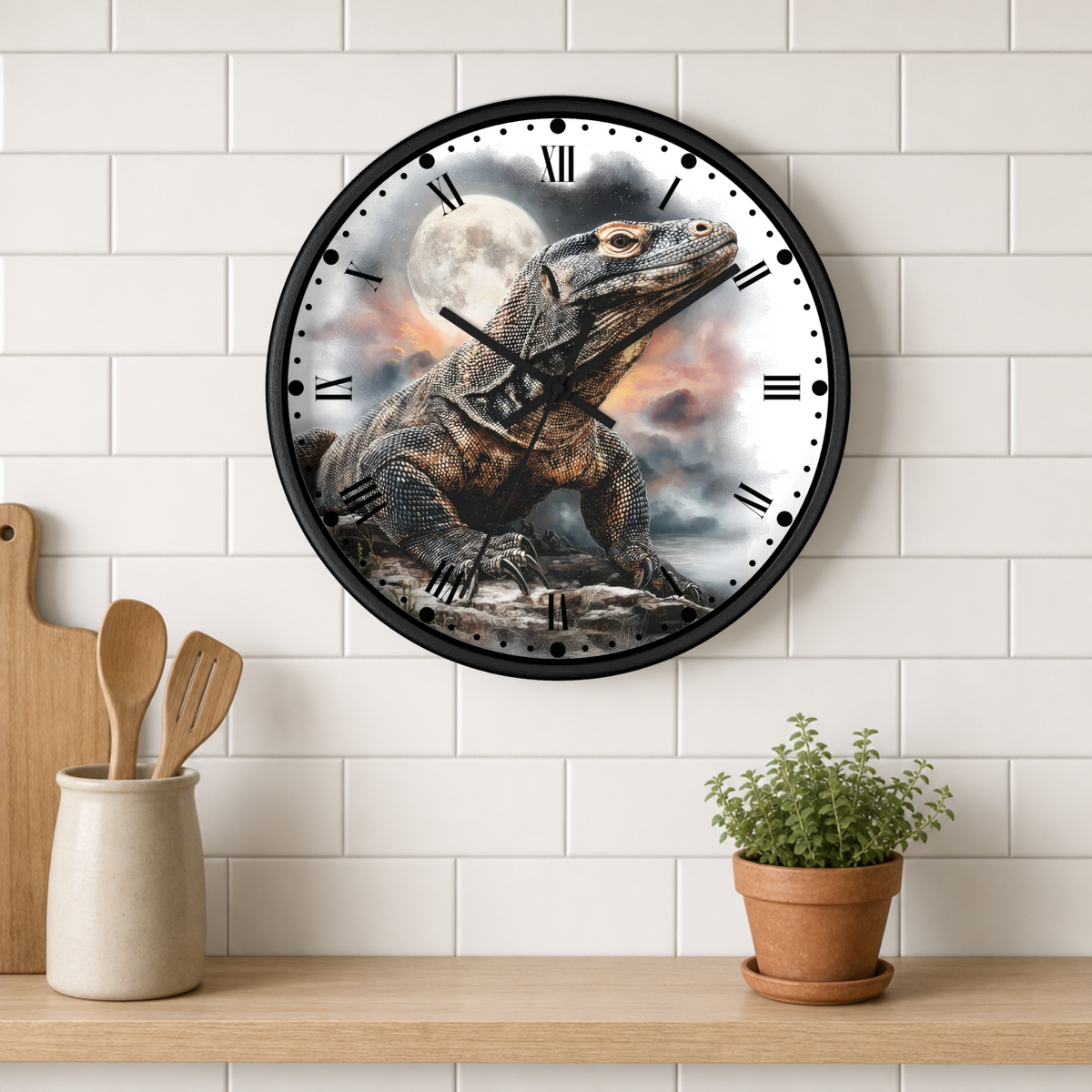 A round wall clock with a black frame and a printed lizard illustration on the face, mounted on a white subway-tile wall above a wooden shelf with kitchen utensils and a potted plant.