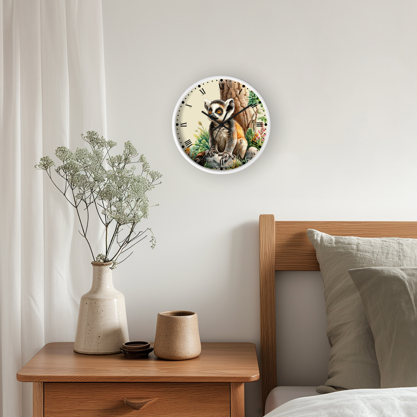 A round wall clock featuring a detailed illustration of a ring tailed lemur, styled on a bedroom wall above a wooden nightstand with a vase of dried flowers.