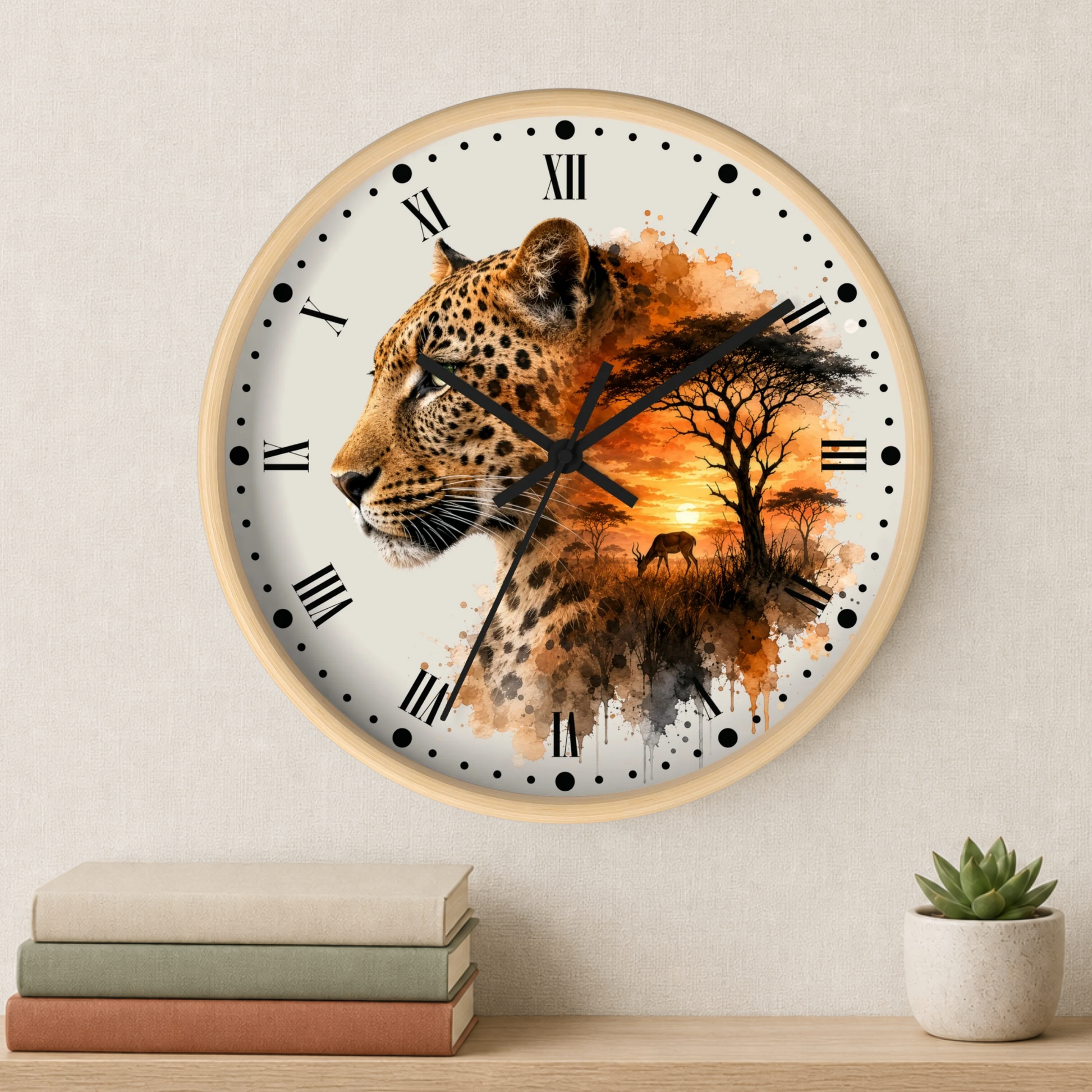 Round wall clock with a light wood frame, featuring a printed design of a leopard blending into a savanna landscape with an orange sunset. The clock is mounted on a textured beige wall above a wooden shelf with stacked books and a small potted succulent.