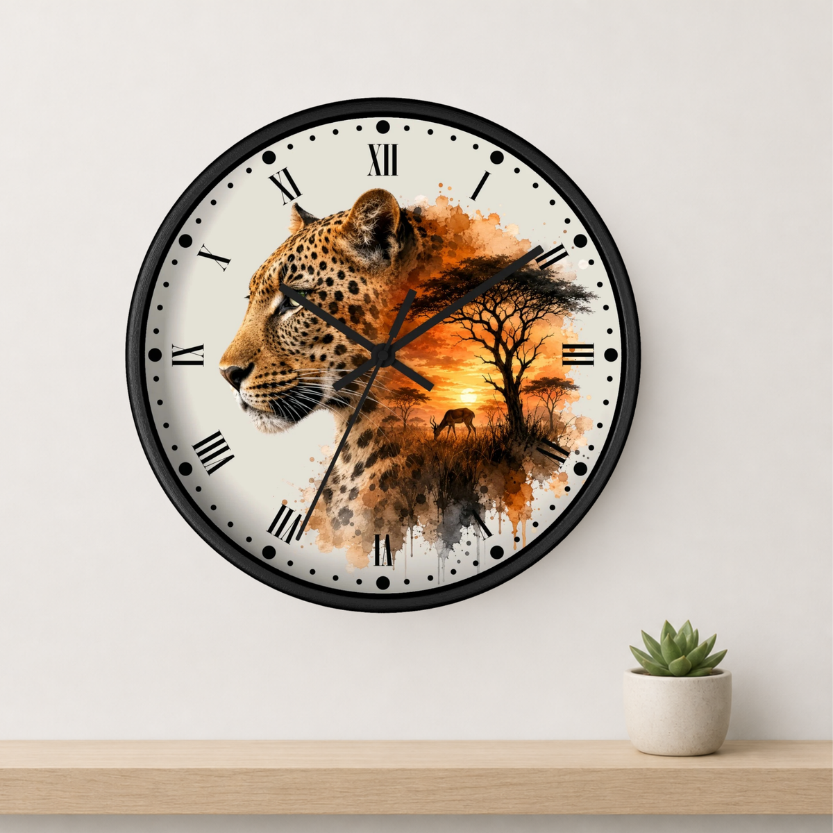 A round wall clock with a black frame and Roman numerals, featuring a leopard and African savanna landscape design on the face, mounted on a light gray wall above a wooden shelf with a small potted succulent.