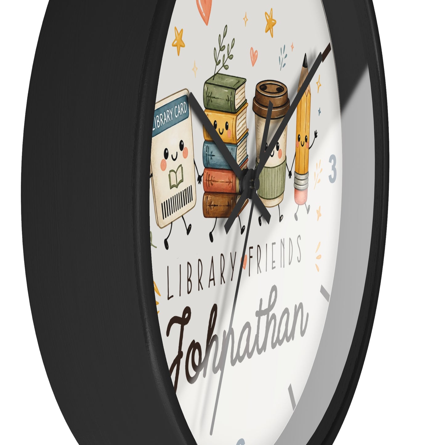 A round wall clock with a black frame and a white face featuring cute illustrated library-themed characters, including books, a coffee cup, and a pencil, with the text 'LIBRARY FRIENDS' and the name 'Johnathan'.