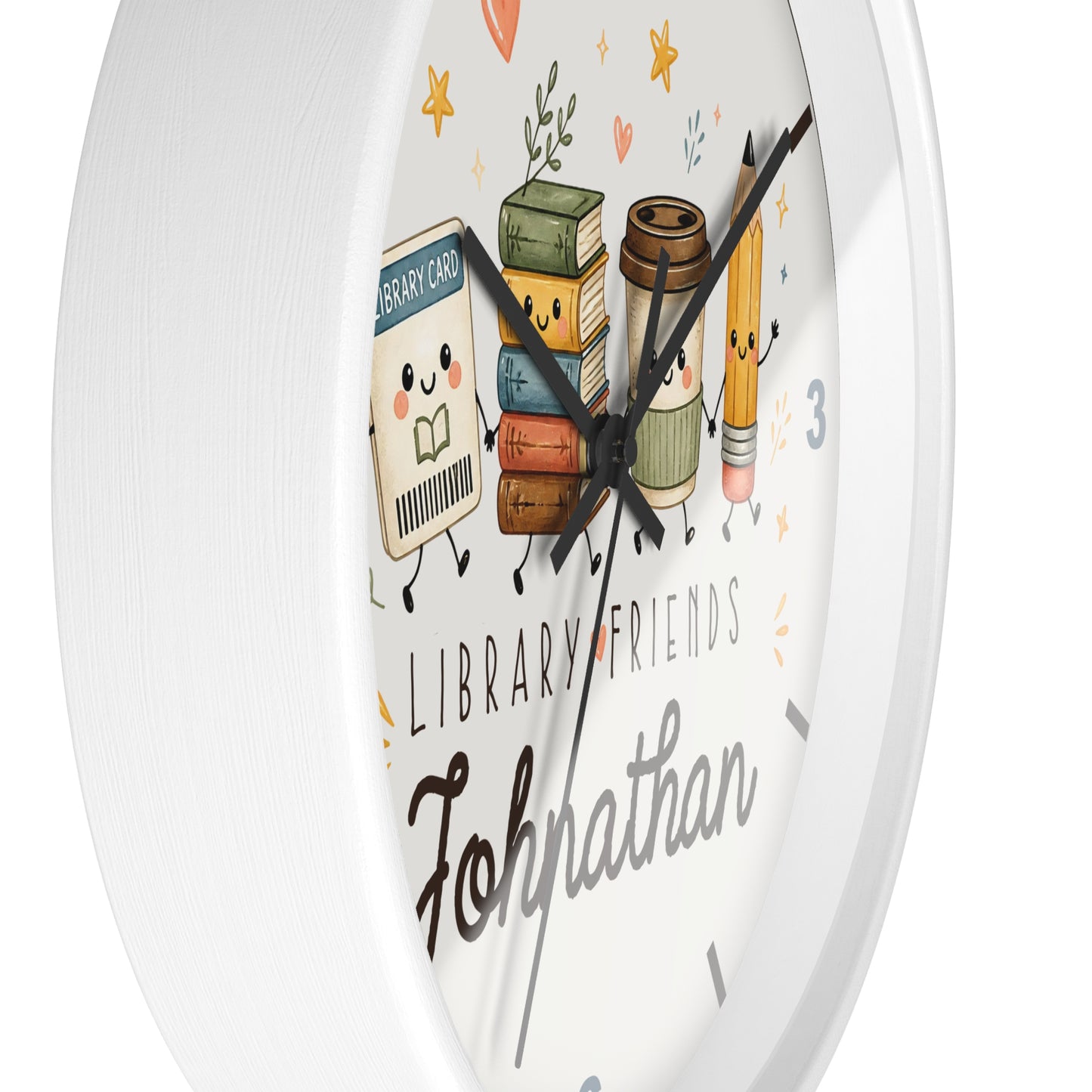 A round white wall clock with a cute library-themed illustration on the face. The design features smiling books, a coffee cup, a pencil, and the words 'LIBRARY FRIENDS' and the name 'Johnathan' in black script.