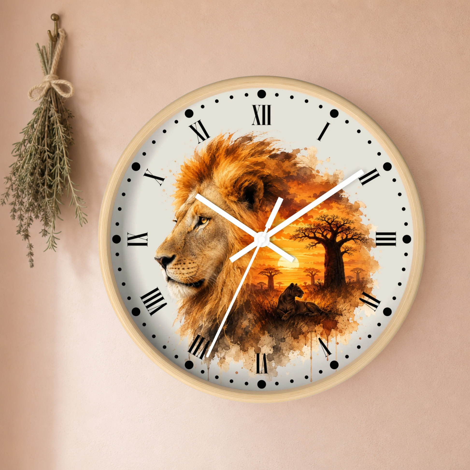 A round wall clock with a light wood frame and a printed design of a lion and an African savanna sunset. The clock is mounted on a beige wall next to a hanging sprig of herbs.