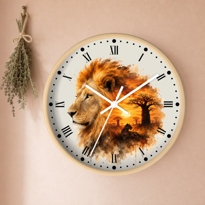 A round wall clock with a light wood frame and a printed design of a lion and an African savanna sunset. The clock is mounted on a beige wall next to a hanging sprig of herbs.