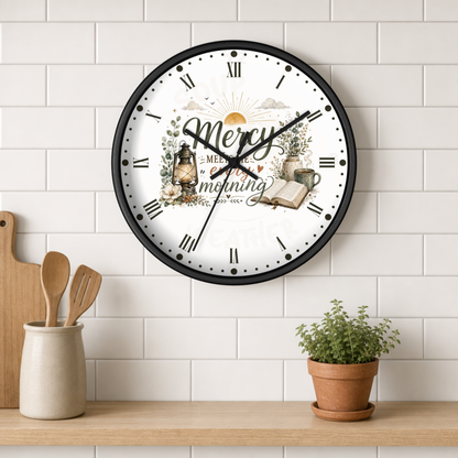 A round wall clock with a black frame and a white face featuring the words 'Mercy in every morning' and autumn-themed illustrations, mounted on a white subway tile wall above a wooden shelf with kitchen utensils and a potted plant.