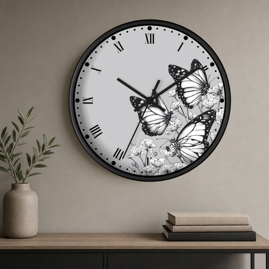 A round wall clock with a black frame and a white face featuring black Roman numerals and butterfly illustrations, mounted on a beige wall above a console table with books and a vase.