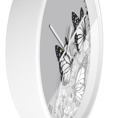 A white round wall clock with a monochrome butterfly and floral design on the dial, shown against a plain white background.