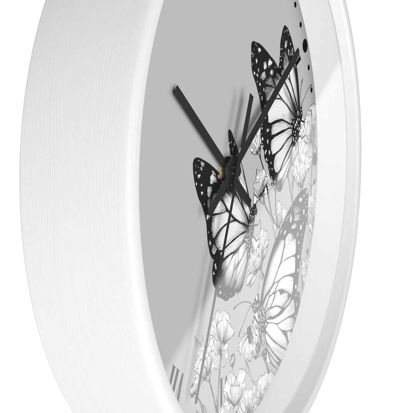 A white round wall clock with a minimalist black and white butterfly and floral design on the dial.