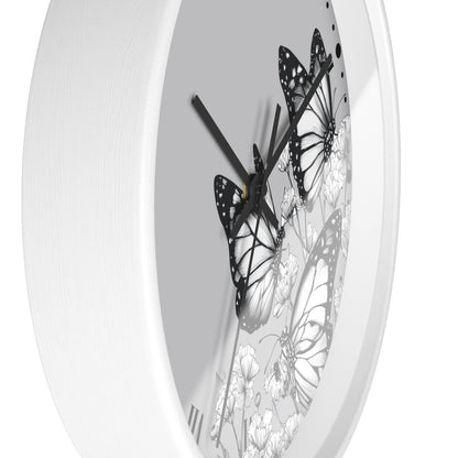 A white round wall clock with a minimalist black and white butterfly and floral design on the dial.