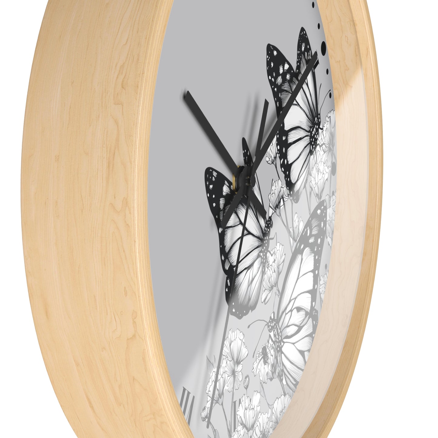 Round wall clock with a light natural wood frame and a gray dial featuring black and white butterfly and floral artwork, shown on a white background.