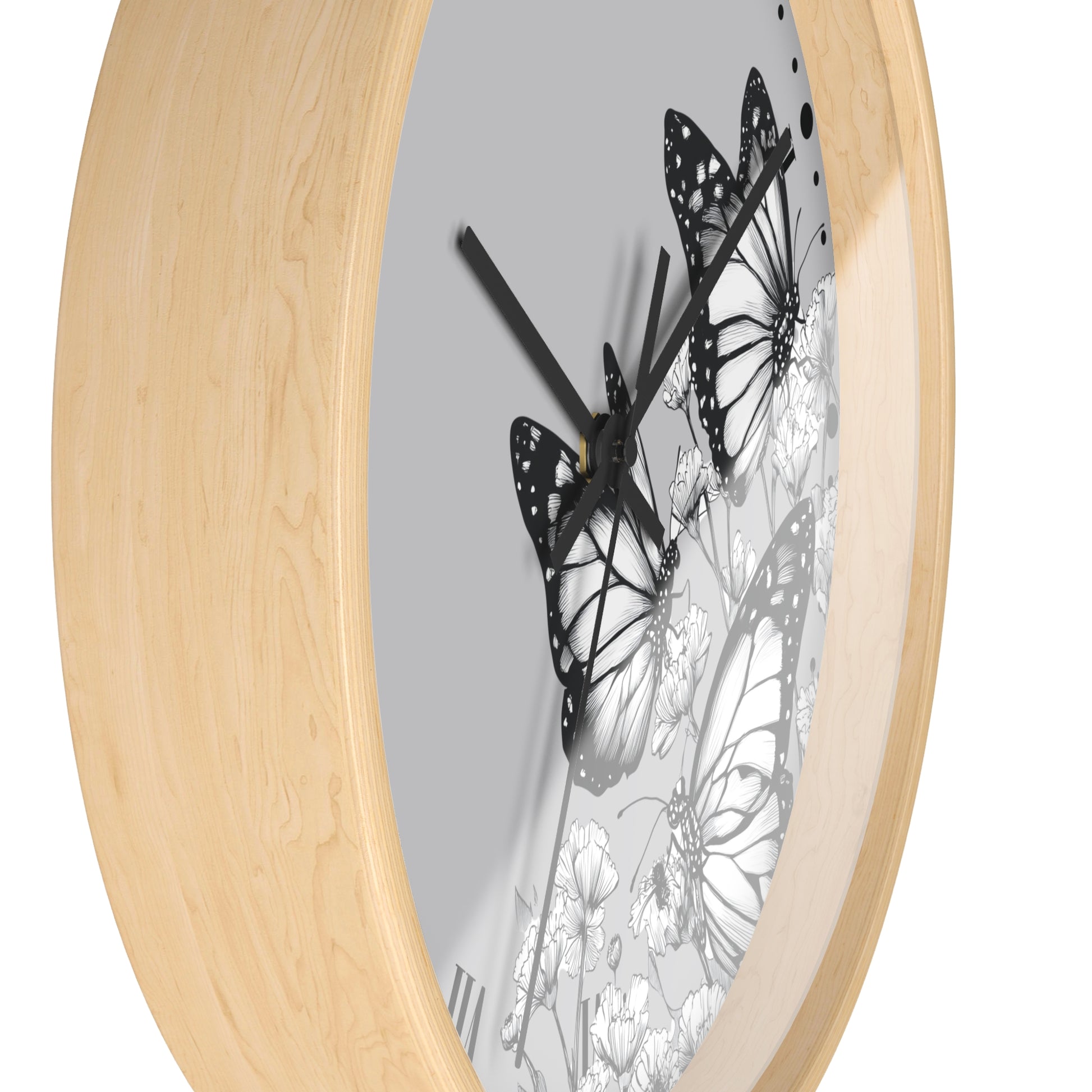 Round wall clock with a light natural wood frame and a gray dial featuring black and white butterfly and floral artwork, shown on a white background.