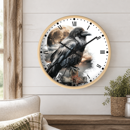 A round wall clock with a light wood frame hangs on a white shiplap wall above a wooden table. The clock face features a detailed illustration of a black raven perched on a weathered post, with a cloudy sky and moon in the background.